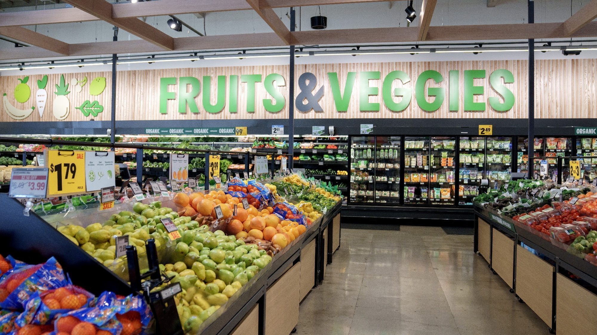 The produce section at Amazon Fresh in Seattle stores showcases an array of fruits and vegetables, from crisp apples and juicy oranges to an enticing variety of greens. A bright sign warmly invites shoppers with the words "Fruits & Veggies.
