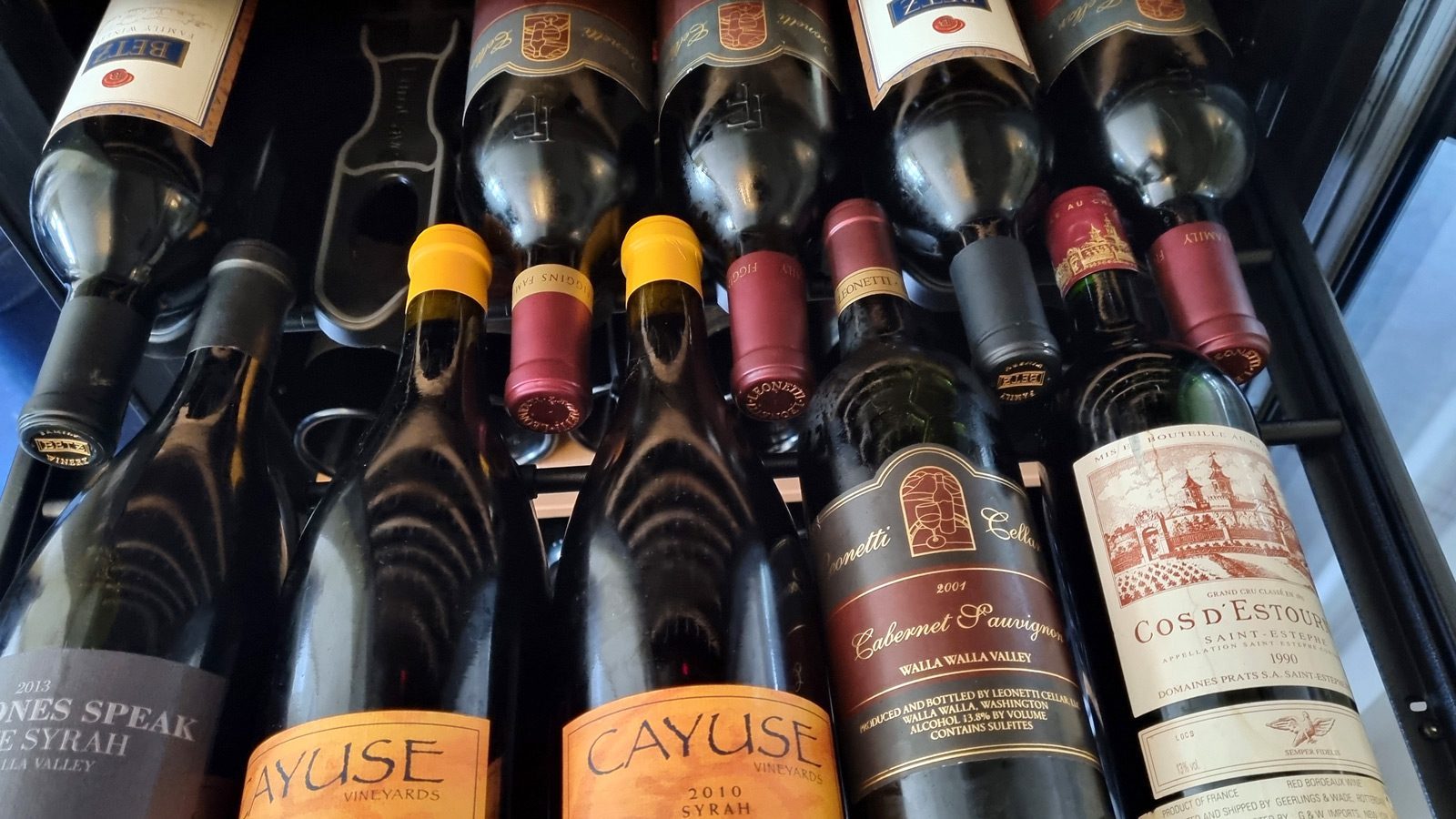 A collection of wine bottles, dubbed the Columbia Crush, is elegantly displayed on a rack, showcasing various labels and vintages like a carefully curated statshot of winemaking excellence.